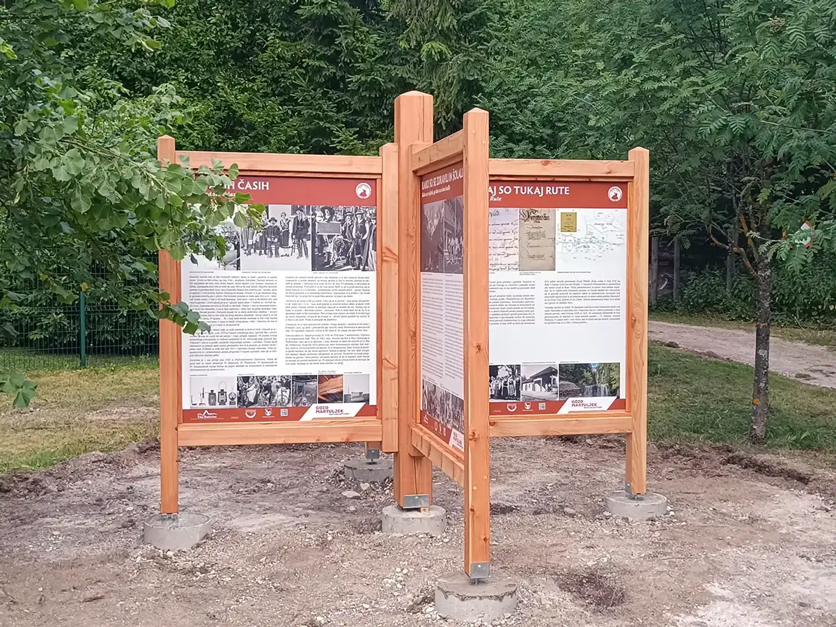 Lesene informacijske table z natisnjenimi panoji in masivno leseno konstrukcijo na prostem.